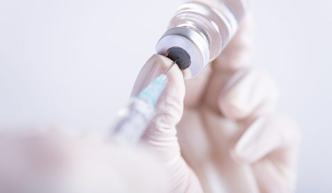 Female doctor hands holding syringe and vaccine. Healthcare And Medical concept.