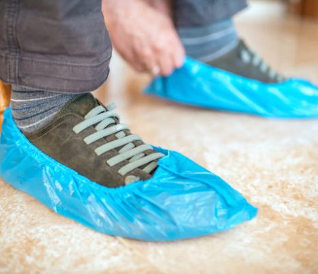 Close Up Of A Man’s Hands Putting On Shoe Covers Close up of a man's hands putting on shoe covers