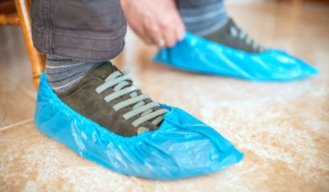 Close Up Of A Man’s Hands Putting On Shoe Covers Close up of a man's hands putting on shoe covers